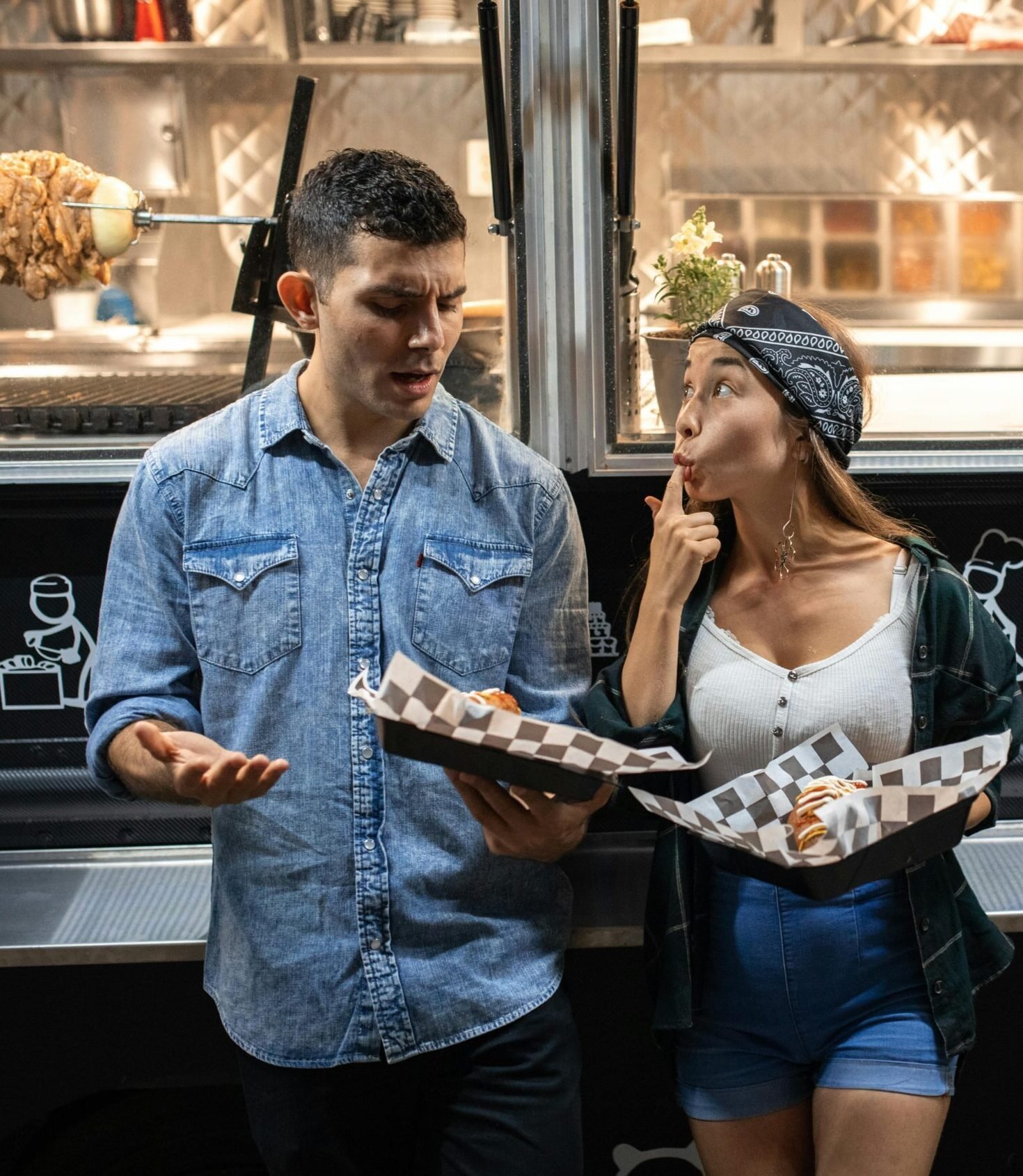 A couple enjoys street food from a food truck at night, sharing fun moments.