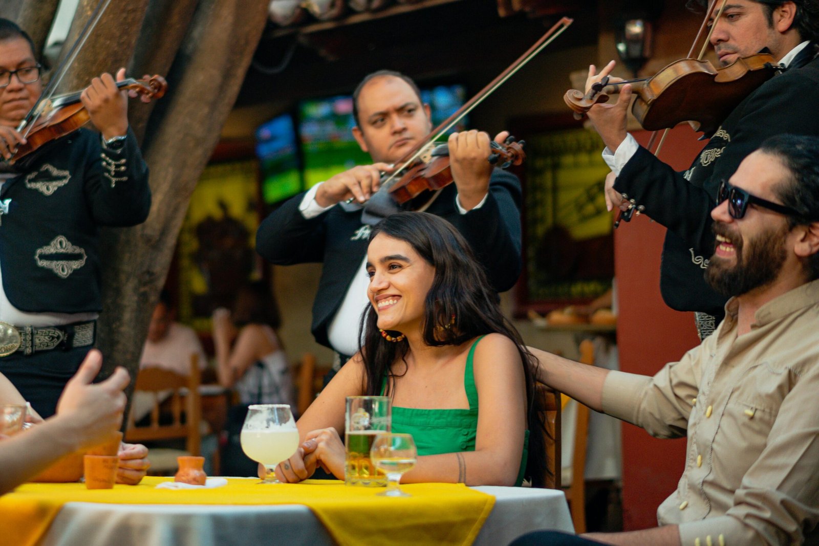 Group of friends enjoying live mariachi music and drinks in a vibrant Mexican restaurant.